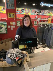 Une des vendeuses en caisse, en parcours d'insertion au sein de notre projet social dans la boutique Emmaüs Sacré Dressing Auray.
